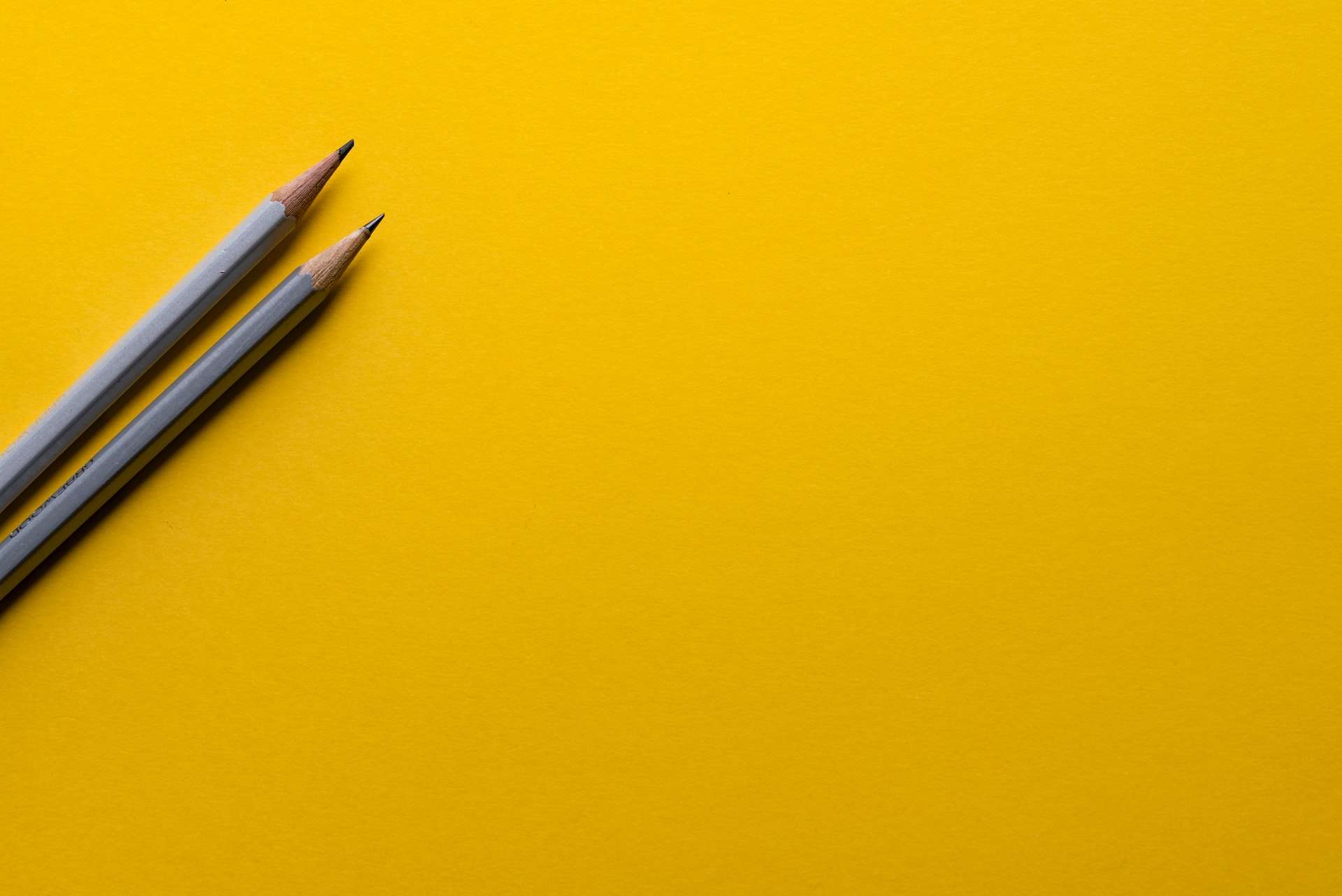 Outsourced marketing two pencils on yellow paper