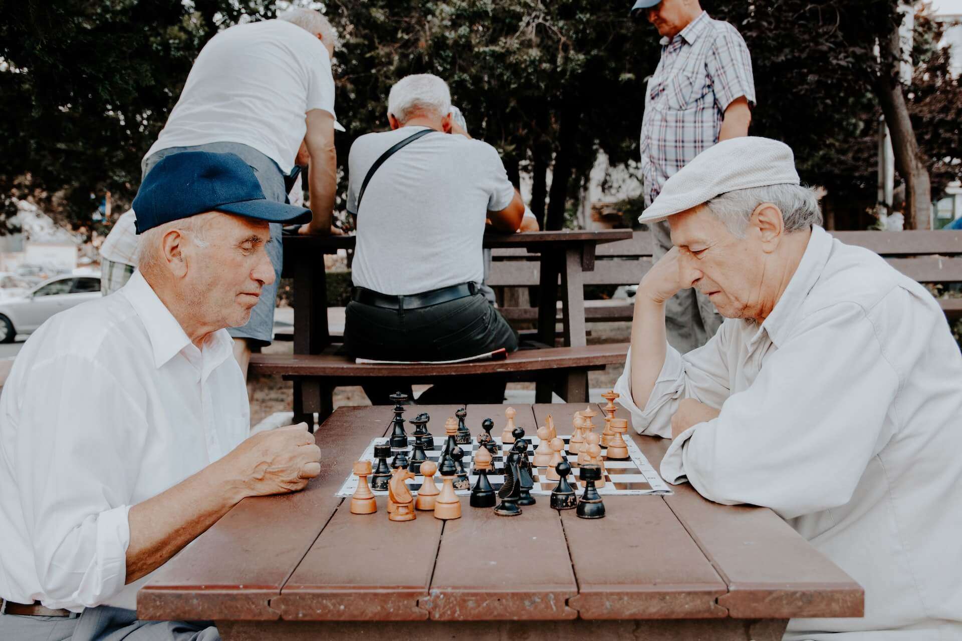 two older men playing chess in a park.