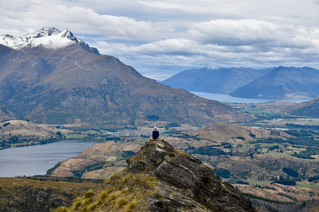 Person sitting on top of mountain over mountain village for CLV blog