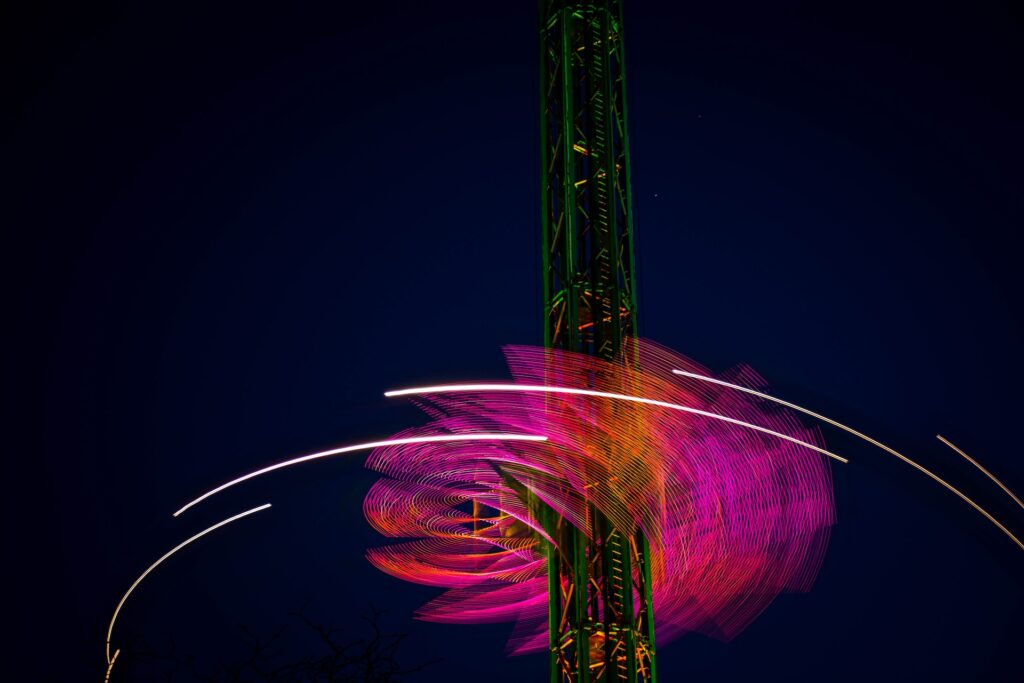 Carnival ride lit up and moving at night. Image for The Growth Function blog.
