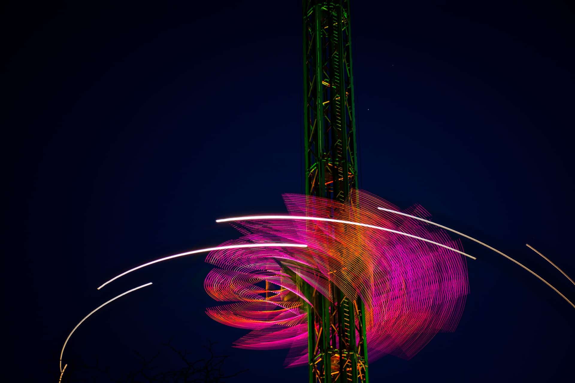 Carnival ride lit up and moving at night. Image for The Growth Function blog.