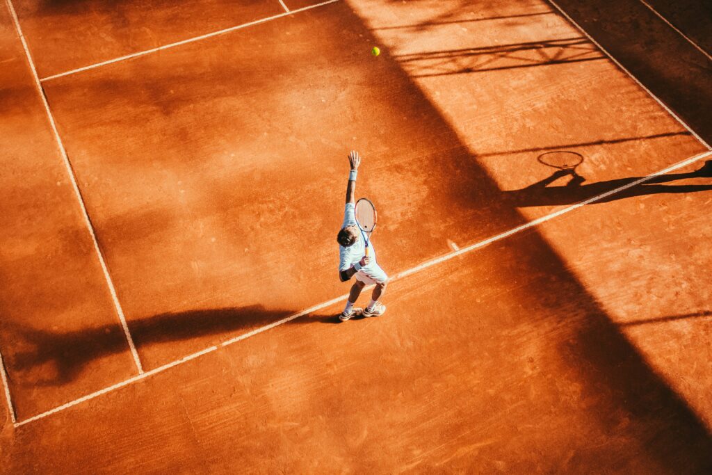 Image of tennis player serving from above on a clay court. Image for sales and marketing due diligence blog.